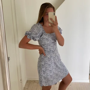 Klänning med blommor  - En magiskt fin blå och vit klänning med blommor. Passar både till vardags och till finare tillfällen en fin sommardag. Älskar hur den ser ut runt halsen. Säljer pågrund av att den är lite för stor för mig runt axlarna. Men passa på! Finns inte längre att köpa🌟 (aldrig använd). 