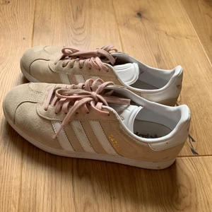 Adidas skor - Ett par beige/smutsrosa adidas skor. Bra skick, lite smutsiga kring sulan och snörena. Finns möjlighet att köpa till nytt skosnöre, vitt eller lila.