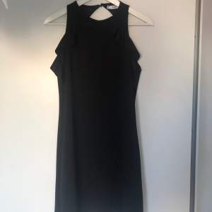 Simpel svart klänning med volanger på sidan och öppen i ryggen. Storlek M och använd en gång.
