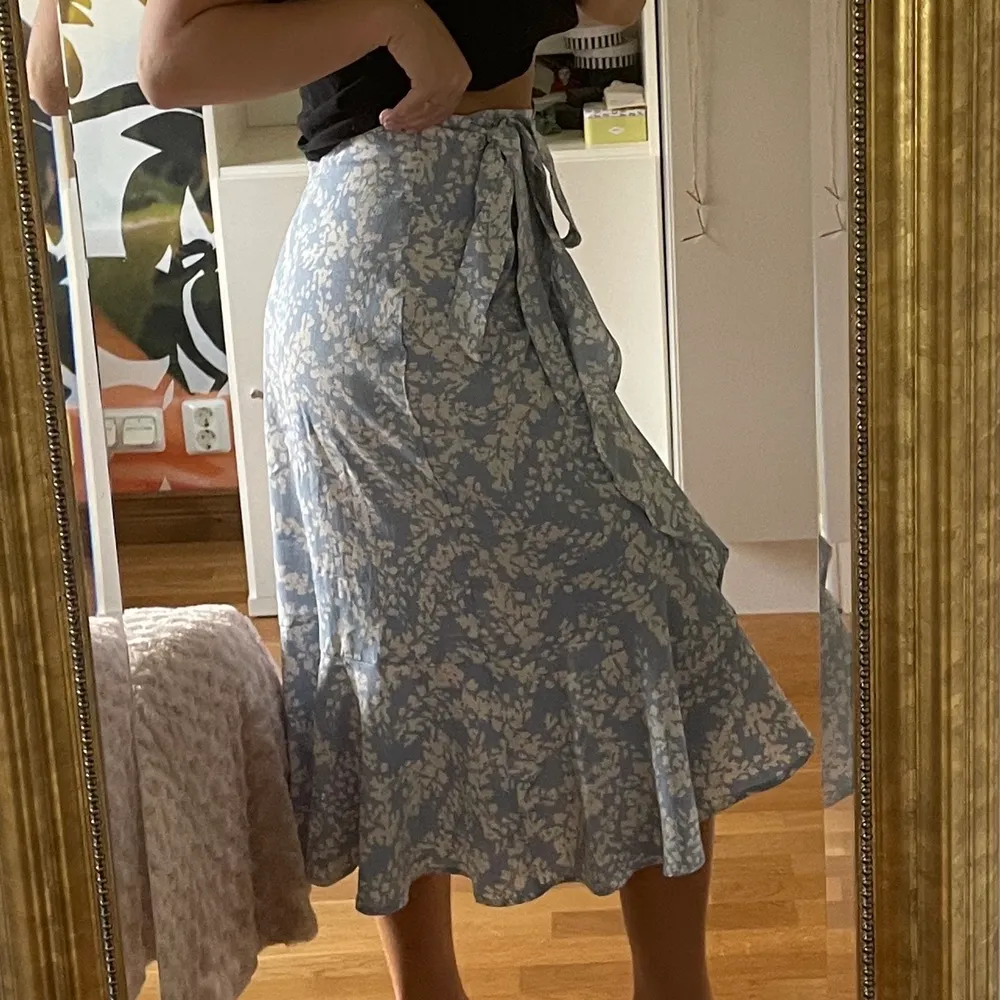 Härlig, vit- och blåblommig kjol som jag köpte på Gina Tricot i juni 2021!!💙 Fin volang och knyte i midjan så den passar mindre och större storlekar!! Säljer pga att den inte kommit till användning mer än 1 gång🤍😇 Nypris: 449. Kjolar.