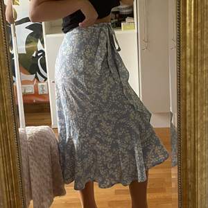 Härlig, vit- och blåblommig kjol som jag köpte på Gina Tricot i juni 2021!!💙 Fin volang och knyte i midjan så den passar mindre och större storlekar!! Säljer pga att den inte kommit till användning mer än 1 gång🤍😇 Nypris: 449