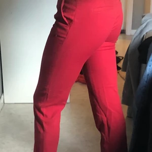 Röda kostymbyxor strl 34/XS - Säljer dessa röda kostymbyxor från H&M då dom inte kommer till användning, dom har en slim fit och är i väldigt fint skick! Jag är 160cm och dom sitter fint i  midjan