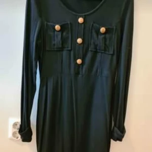 Klänning Chiara Forthi Milano strl S. - Kort figursydd klänning i mjukt tyg material och gulddetaljer från Chiara Forthi Milano i strl S som är använd vid ett tillfälle.