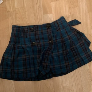 Blå och brun kjol - Jättefin kjol som tyvärr inte passar mig. Fyra knappar fram och ett tygbälte som man kan använda för att dra åt kjolen i midjan. Från märket Eve vilket jag ej hört talas om förr