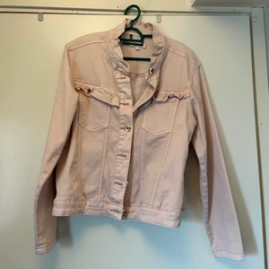 jeans jacka - Super söt jacka perfekt för barnen. Jackan är i en babyrosa färg och har volang detaljer på de olika fickorna. Knapparna är alla i en guldfärg