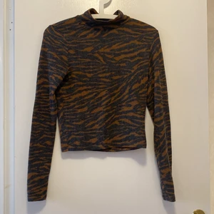 Tigermönsrtad halvpolo - En tigermönstrad halvpolo i fleecetyg. Superskön och mjuk! Nästan aldrig använd! Väldigt varm och skön!