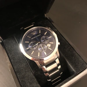 Emporio Armani klocka  - En Armani klocka med blott öga och metall armband. Original pris ca 3000kr. Användes sällan och har inga repor på glaset. Får med en låda till klockan som tyvärr är trasig, går inte att stänga hela vägen men är snygg prydnad för att visa klockan. Får även med en transport låda med förlängnings bitar till armbandet samt en bok som sammanfattar klockans alla funktioner. Klockan kan ta tid och liknande. 