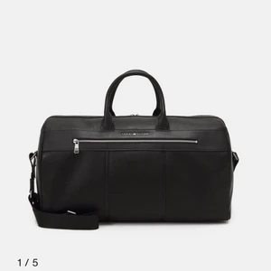 En tommy hildiger väska - Den väska som jag har aldrig använt har fortfarande kvitto, säljer på grund av att vi vill ha en brun väska istället för en svart. 61x38 cm, bud eller direkt köp för 1000kr kan fraktas då köparen står för frakt och kan mötas upp. Ordpris 2295 men säljer för 1000