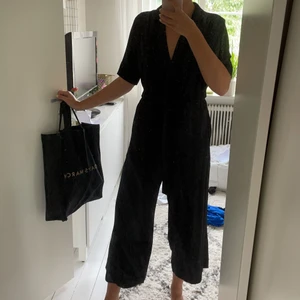 Svart omlottjumpsuit från Weekday  - Svart jumpsuit från Weekday med croppade ben, enbart använd en gång