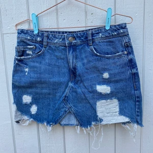 Kort jeanskjol - Kort jeanskjol med slitningar. Förstärkt på insidan för att slitningarna inte ska fransas upp. 