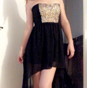 Medium svart klänning  - Svart klänning kort fram lång därbak med glitter decor vis brösten. Medium i storlek. Använd noll gånger, gick ner för mycket i vikt innan jag hann använda den och nu passar den inte längre. 130 utan frakt vill jag ha men pris diskutabelt. 