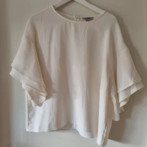 Blus H&M - Lite finare blus i 100 polyester, fina detaljer på armarna med dubbla volanger, Äggskalsvit i fint skick.