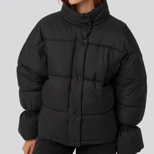 NA-KD Pufferjacket - Trendig pufferjacket i så gott som nytt skick. Svart med elastisk armdetalj. Har även ett elastiskt band längst ner som man kan spänna in. Köpt i december 2020. Säljer då jag inte använder den. OBS första bilden är lånad från NA-KD. 