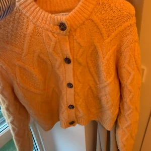 Stickad tröja  - Hej! Säljer nu en supersnygg stickad tröja från zara i storlek S. På kameran ser den lite mer gul ut men är pastellorange. Den har fina utsmyckande knappar och man kan ju då även ha denna stickade tröja som en kofta då knapparna går att knäppa upp. Den är precis som ny i skicket då jag bara använt den 2-3 gånger och är just därför jag säljer den. Den ser ut att sticka ganska mycket men i själva verket sitter den väldigt bekvämt mot huden. Hör av dig om du är intresserad!😊💕