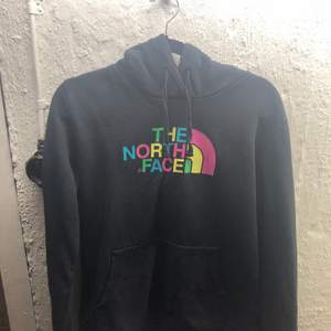 Supercool the north face hoodie i färgen svart med färglada bokstäver på! köpt på beyond retro för ett år sen och säljs då den ej kommer till användning!                lite ”stelt” tyg  pga vintage 