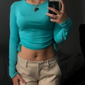 TURKOS TOPP FRÅN PLT - Säljer denna jättesöta turkosa tröjan som man kan dra i midjan! Den är i storlek 36 och är från Pretty Little Thing!