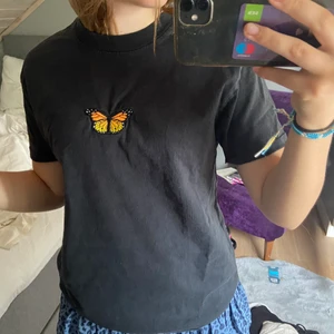 Brandy melville topp - En svart brandy melville topp med en orange fjäril på. Tjockare i materialet. Oversiezed och använd ett fåtal gånger💞 du står för frakt