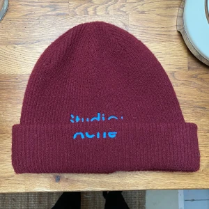 Acne Mössa - Vinröd Mössa med Blå text från Acne Studios. Såå fin men använder tyvärr inte längre, lappen i mössan sitter löst men annars i toppskick! Kom med bud:) köpare står för frakt