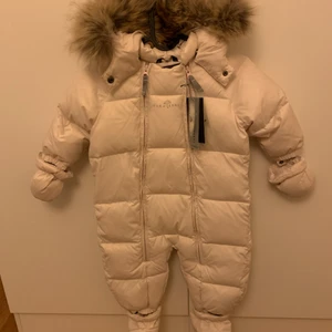 Ver de Terre vinteroverall rosa, oanvänd - Ver de Terre vinteroverall rosa, oanvänd. Dunoverall med pälskrage. Tillhörande fot- och handvärmare är avtagbara.