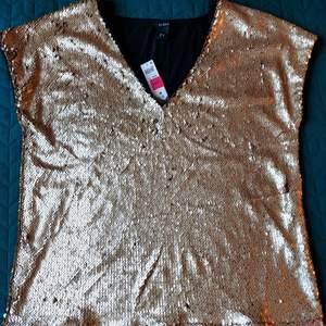 Brand new blouse from Lindex. Never worn, with price tags in place. Clean, no defects.  Beautiful semi-mat golden sequins on the entire front. Black plain fabric on the back.  Lining under the front.  Fabric: 95% viscose, 5% elastan.  Size: M (for loose fit, per info on the tag), fits L too (closer to body).