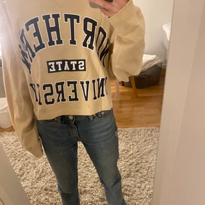 Collegetröja  - En beige collegetröja med mörkblå text på.