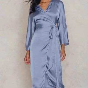 Duvblå silkig klänning av Hannalicious  - Såå fin klänning från NA-KD, hannalicious. Kimono som Knuts i midjan och tillhörande underklänning. Sparsamt använd. Kan användas som finare nattlinne eller till fest. Superskönt svalt material och den perfekta blåa färgen😍säker pga används för sällan. Storlek 34men passar även en 36 och ev en liten 38.