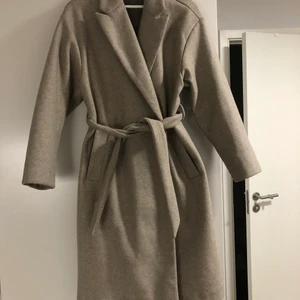 Beige kappa - Kappa från Vero Moda. Går förbi knäna på mig som är 165cm. Använd en vinter. Passar alla från xS till M