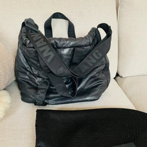 Väska Alexander Wang x HM - Svart läderväska från kollektionen Alexander Wang x HM. Fack med dragkedja både fram och bak. Flera fack inuti. Har två korta handtag och ett långt justerbart. Tillhörande dustbag i nät tillkommer också.    