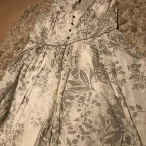Klänning  - En klänning med enfärgkombination på vit och grått och blomster tema med en dragkedja vid sidan är det jag har och erbjuda 😁 