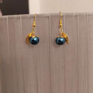 Vackra örhängen. Marinblå pärla med guldhatt och guldlöv. 