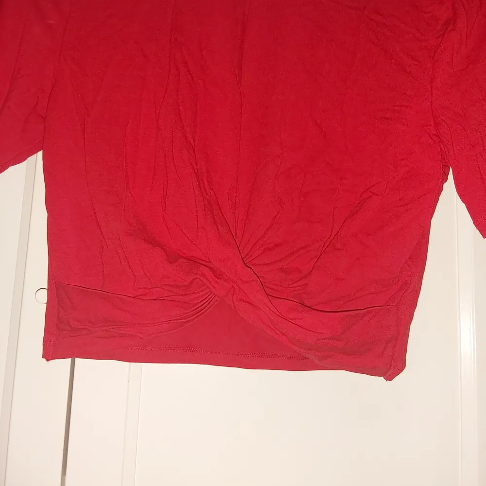 Säljer denna söta topp från H&M i röd färg. Går i omlott i nedre delen av tröjan. Materialet är stretchigt så passar nog fler storlekar. Aldrig använd, endast prövad. Fraktpris tillkommer! Skriv gärna privat för fler bilder!💕. Toppar.