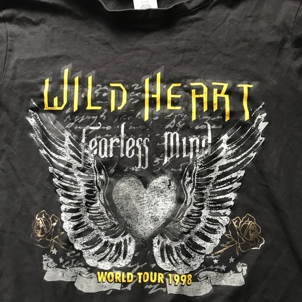 En svart tröja med ett tryck på. Citat: Wild Heart Fearless Mind, World Tour 1998. Hade användt den om den passade i storleken men tyvärr för liten. Inte använd mycket men lite urtvättad så nytt pris!✨. T-shirts.