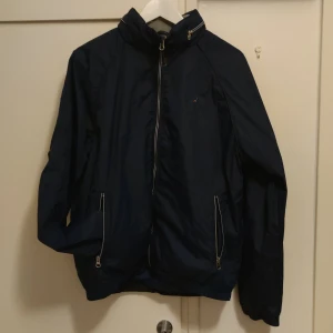 Boomerang - Snygg, mörkblå regnjacka från Boomerang med infälldbar huva i stl L, men något liten i stl. Herrmodell och den är i väldigt fint skick.