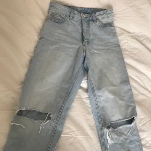 Jeans från Monki - Säljer ett par ljusblåa jeans från Monki i storlek 24 (gjort hålen själv)