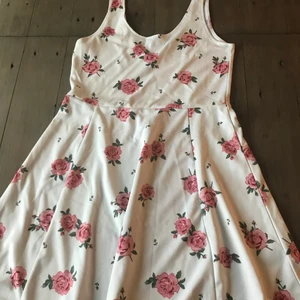 Vit blomning klänning  - En vit klänning med rosa rosor på och låg rygg. Köparen står för frakten 