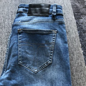 Jeans från Tiger of Sweden. - Blåa jeans från Tiger of Sweden. Välanvända. Hål vid hällan, se bild 1. Där av priset. Låg midja. Storlek 29 längd 34. Katt finns i hemmet.  