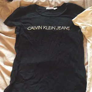 Två Calvin Klein thsirt, på den svart T-shirten är texten lite sprucken. 
