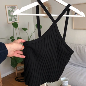 Svart croptopp - Svart cropptopp med ”kryss” framför halsen. Använd endast en gång.