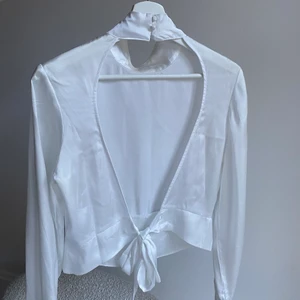 Satin topp NAKD  - Vit satin blus/topp från NAKD med öppen rygg och snörning. Fina detaljer på ärmen och i nacken med fina knappar. Bra skick använd ca 2 gånger, perfekt för fest! 
