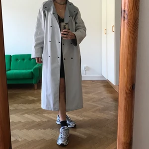 Trenchcoat  - Jättefin trenchcoat i ljusblå/ljusvit/ljusgrå. Passar helt utmärkt som både sommarjacka och höstjacka. Man kan knäppa upptill som en polo vilket ger den en värmare effekt! Jag är 162 och sitter sååå snyggt på. 