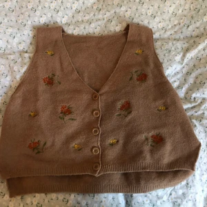 Brun stickad väst - Stickad väst med blommig broderi detalj. Lös passform och superskön.