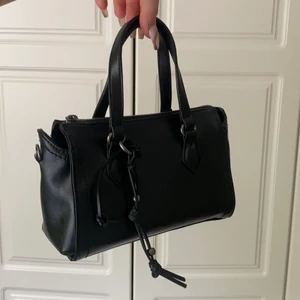 Zara väska - Jag säljer min snygga väska från Zara, som har läderimitation. Den är endast använd en gång, så den är i nyskick. Den har både ett kort band, samt ett långt band man kan justera längden på. På insidan har den ett innerfack. Jag säljer den för 160kr+ frakt (Har ett bud på 180kr + frakt)