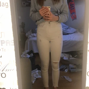 Vita jeans - Ett par vita jeans med hål vid ett knä och vid fickorna. Jeansen är använda ett få tal gånger och är i ett bra skick. Lite oklart vart de är ifrån men de är i storlek 36. De är högmidjade. De kostar 150+ 30 kr i frakt