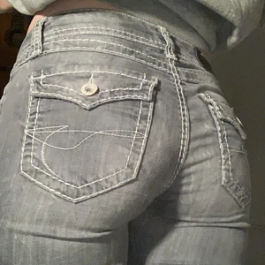 Lågmidjade jeans - Gråa lågmidjade utsvängda jeans med vita stygn. 