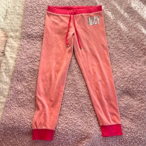 Juicy Couture Rosa Velour Byxor - Säljer även mina rosa Juicy Couture byxor pga för liten storlek. Köpta på Juicybutiken i London för 1099 kr. Har använts väldigt få gånger och är i superfint skick. Har loggan i silvriga paljetter på framsidan och fickor med knappar på rumpan. Storlek Medium.