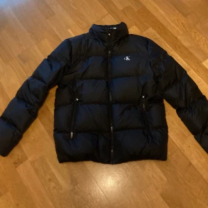 Calvin Klein pufferjacka - En mysig och tjock Calvin Klein pufferjacka(har som garanterat håller värmen jackan är storlek Large och passade mig perfekt 75 kg 175 cm. Säljer den då den förtjänar att användas mycket mer, köpte den för ett år sen men har använt den mindre än 10 gånger och är nästintill nyskick. Inga defekter finns, jag säljer den för 400+ frakt eller meetup i Helsingborg. Ny säljare på Plick men har referenser sen tidigare om det begärs: för flera bilder tex passform så skriv om