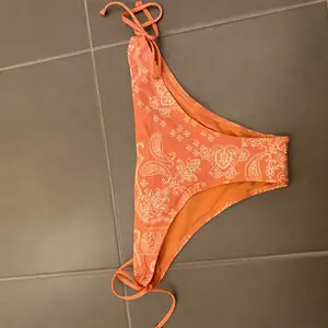 Peachfärgad bikiniunderdel med snörning i sidorna. Köparen betalar frakten 