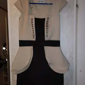 Storlek M, svart och beige fodral klänning i skön stretching material med nitar som detaljer på framsidan. 50 kr 