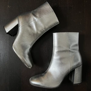 BOOTS - Silvriga boots med klack i äkta läder. Använda en gång pga kan ej gå i klackar. klacken är 8-9 cm, tyvärr lite repiga på ena skon, kan skicka fler bilder! nypris 800kr