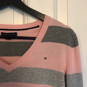 Randig Tommy Hilfiger Tröja - Rosa-, vit- och grårandig tröja ifrån Tommy Hilfiger i storlek M. Sparsamt använd så i mycket fint skick! Köparen står för frakten. 